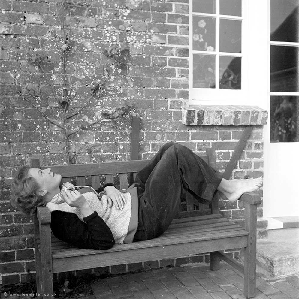 Lee Miller reclining on a bench outside Farleys House